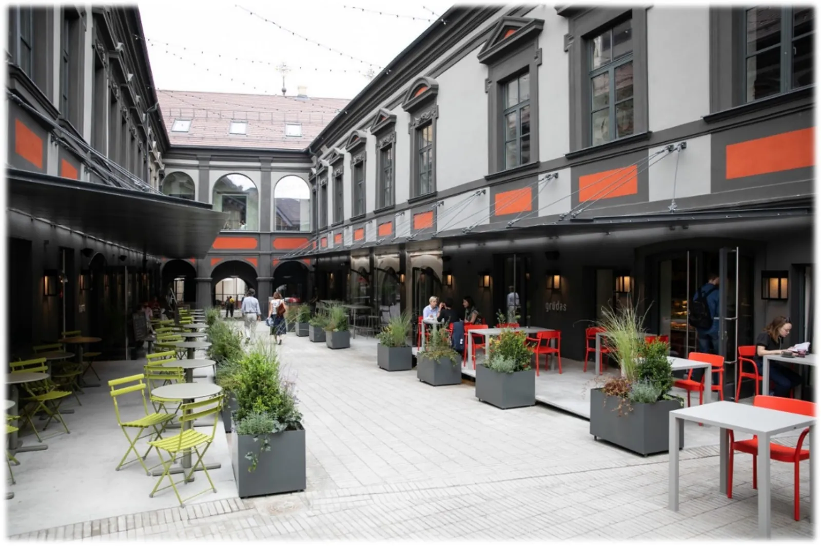 Courtyard elevation with a dark glazed facade and full-height window units behind seating