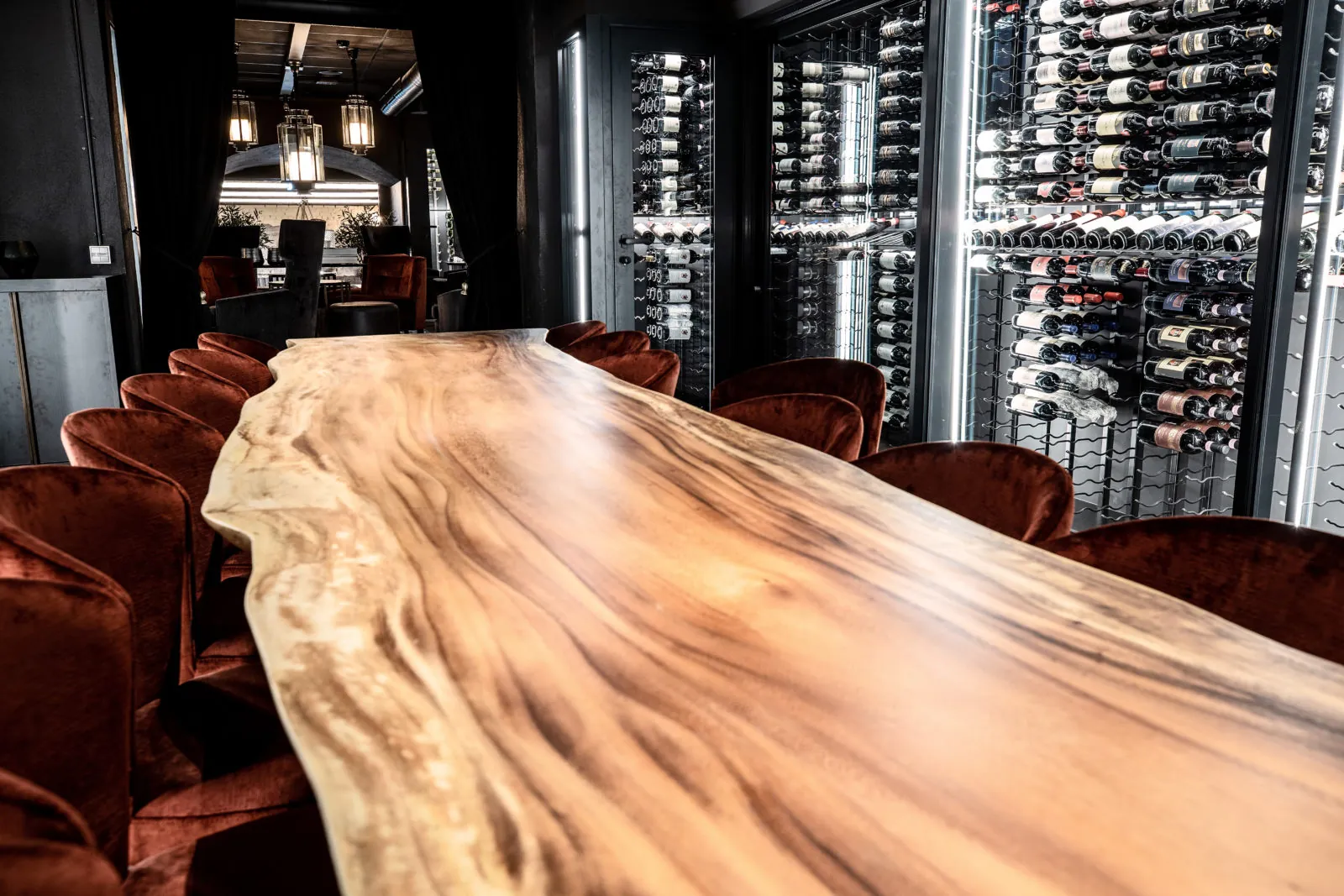 Dark interior lined with glass-fronted display cabinets around a solid timber table