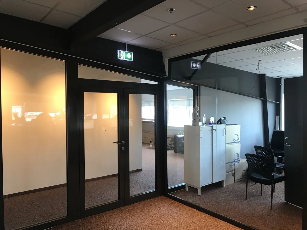Office floor divided by dark-framed glazed partitions with a glazed double door