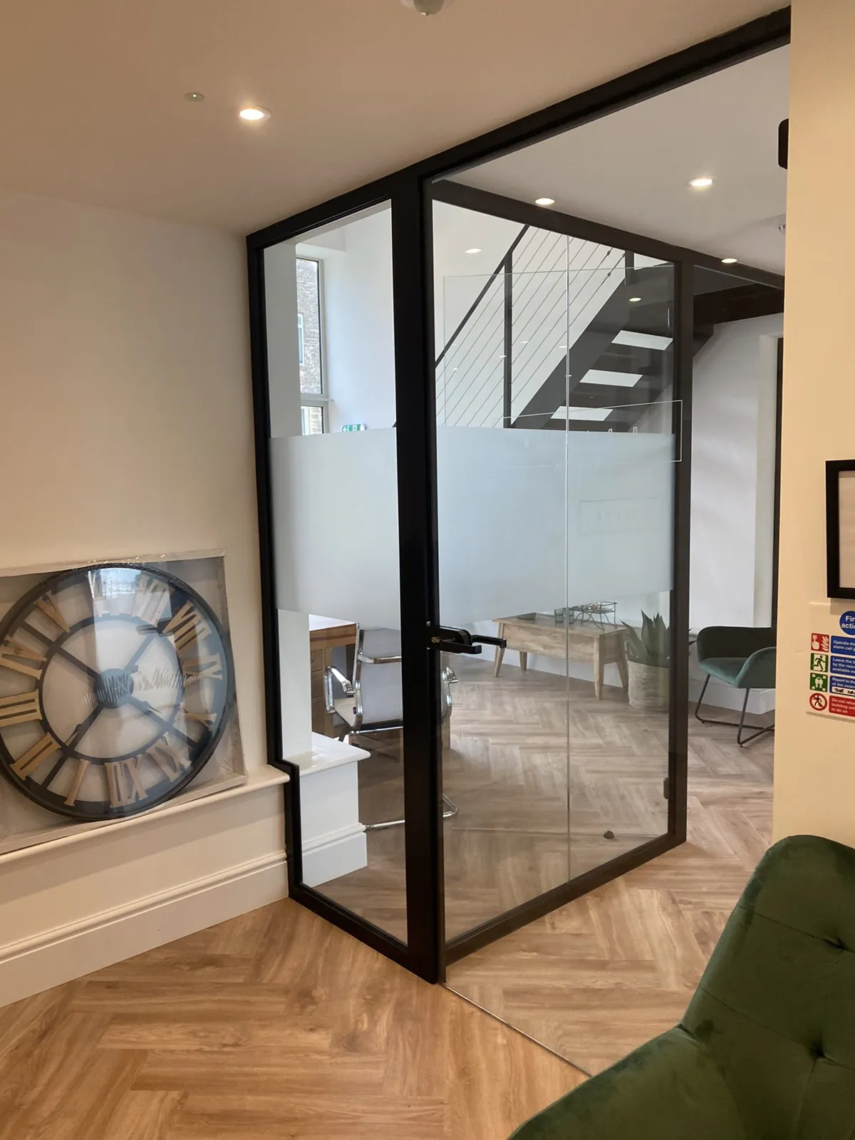 Single glazed door leaf in a black frame, hung within a run of fixed glazed partition panes