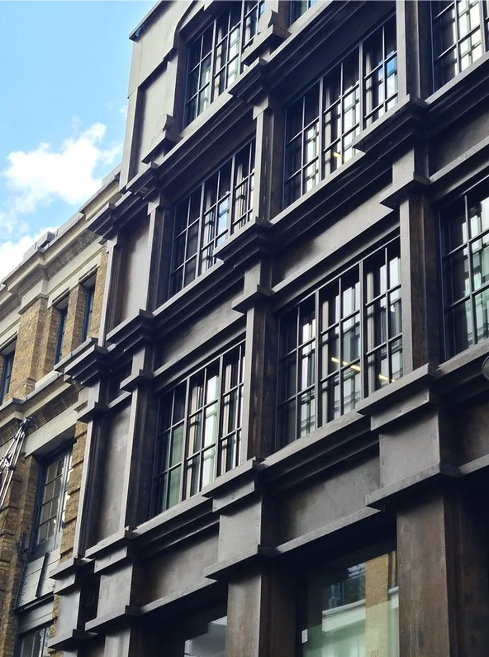 Detail of a dark metal-clad facade showing industrial-style glazed units and their framing