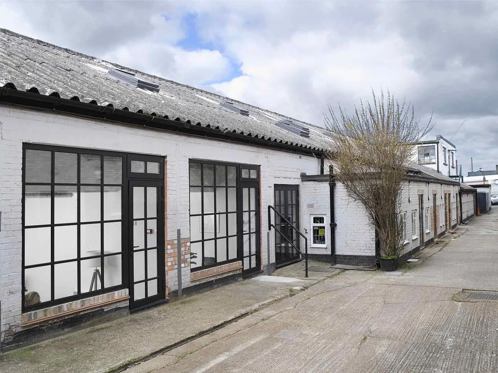 Run of white-painted brick units with repeated black-framed multi-pane doors and windows